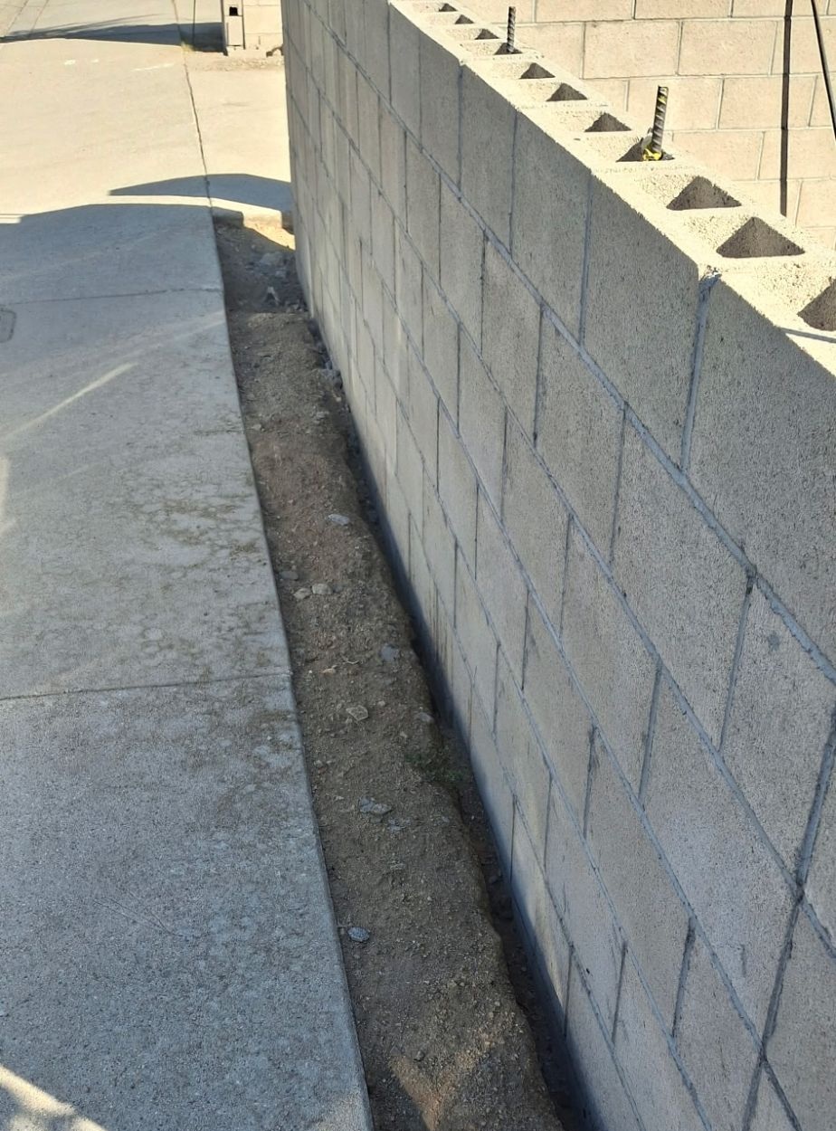 New concrete block wall with steel rebar extending from the top course
