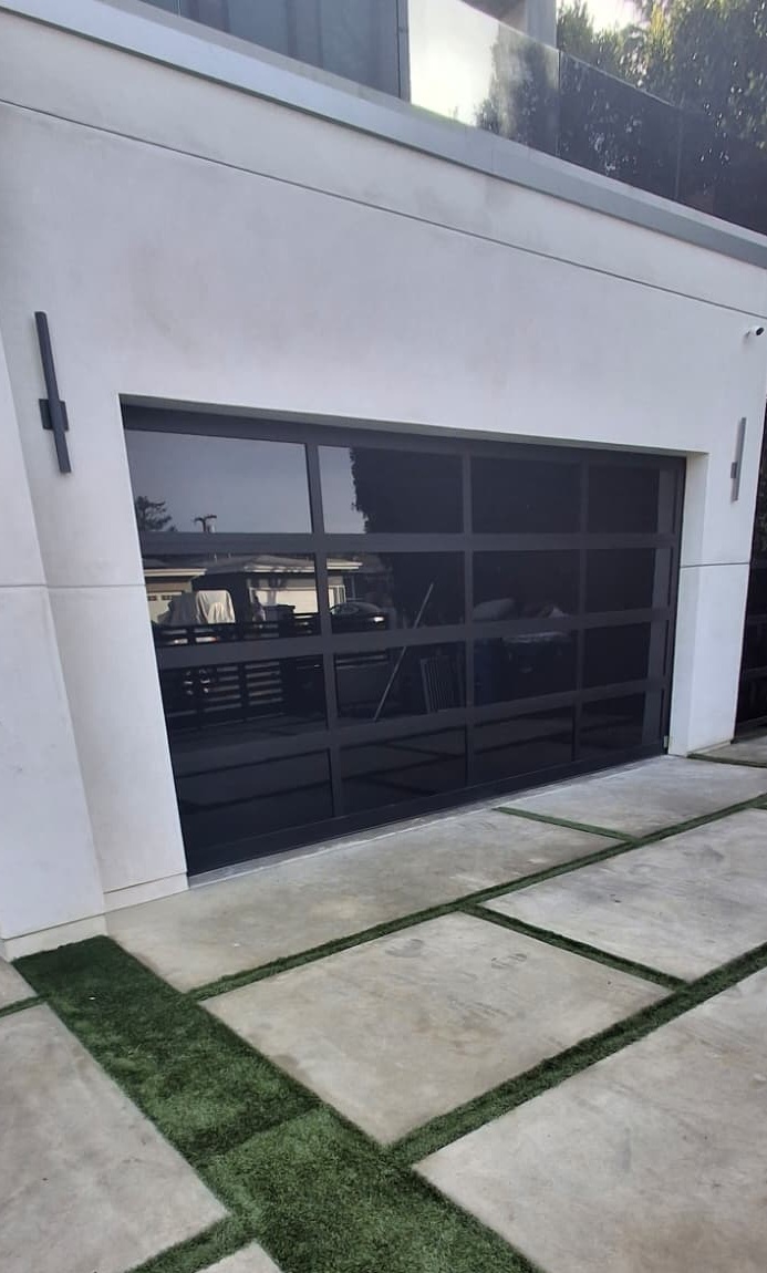 Black-frame dark glass garage door on a modern white home