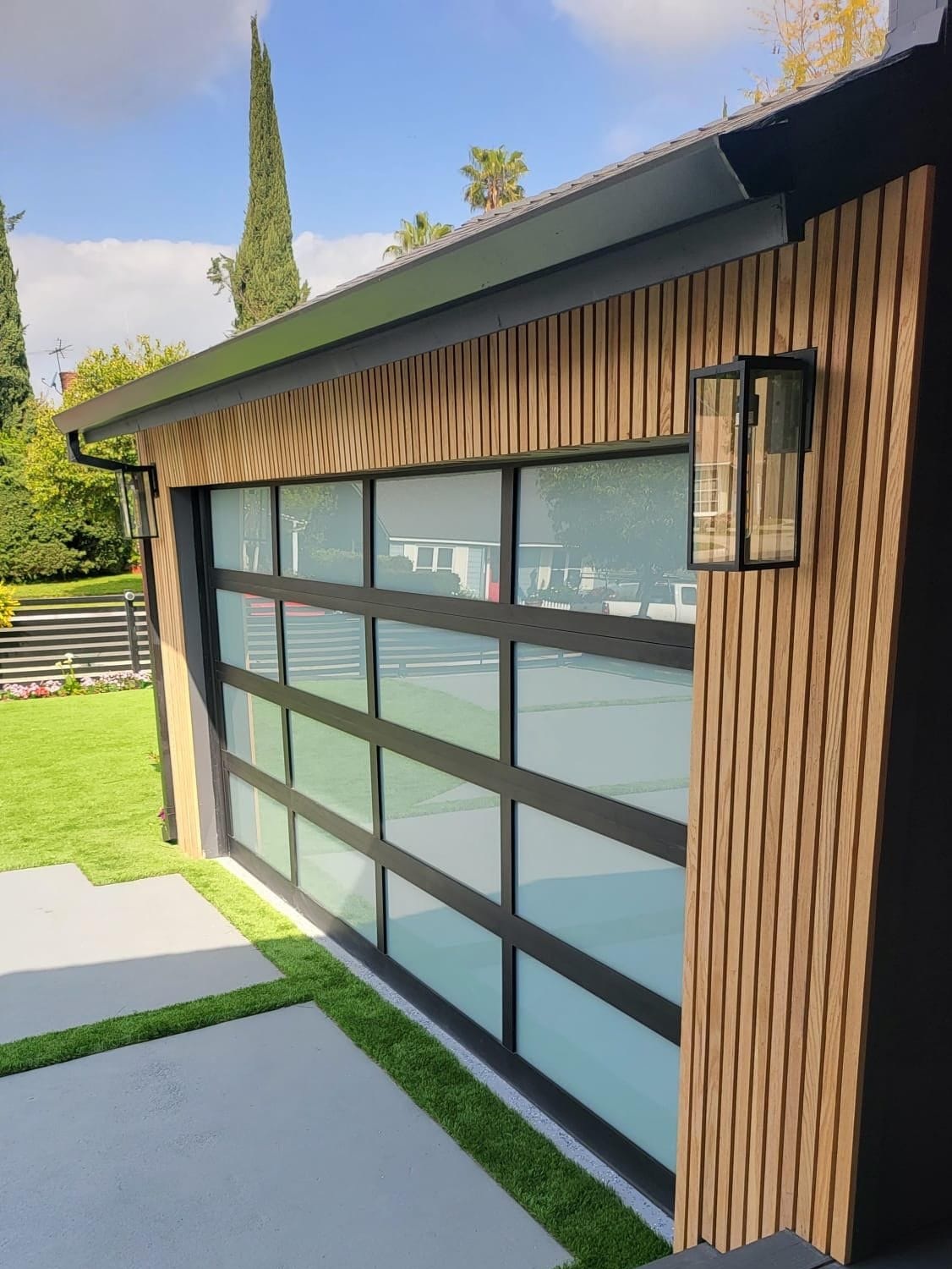 Black-frame frosted glass garage door on a home with vertical wood slat siding
