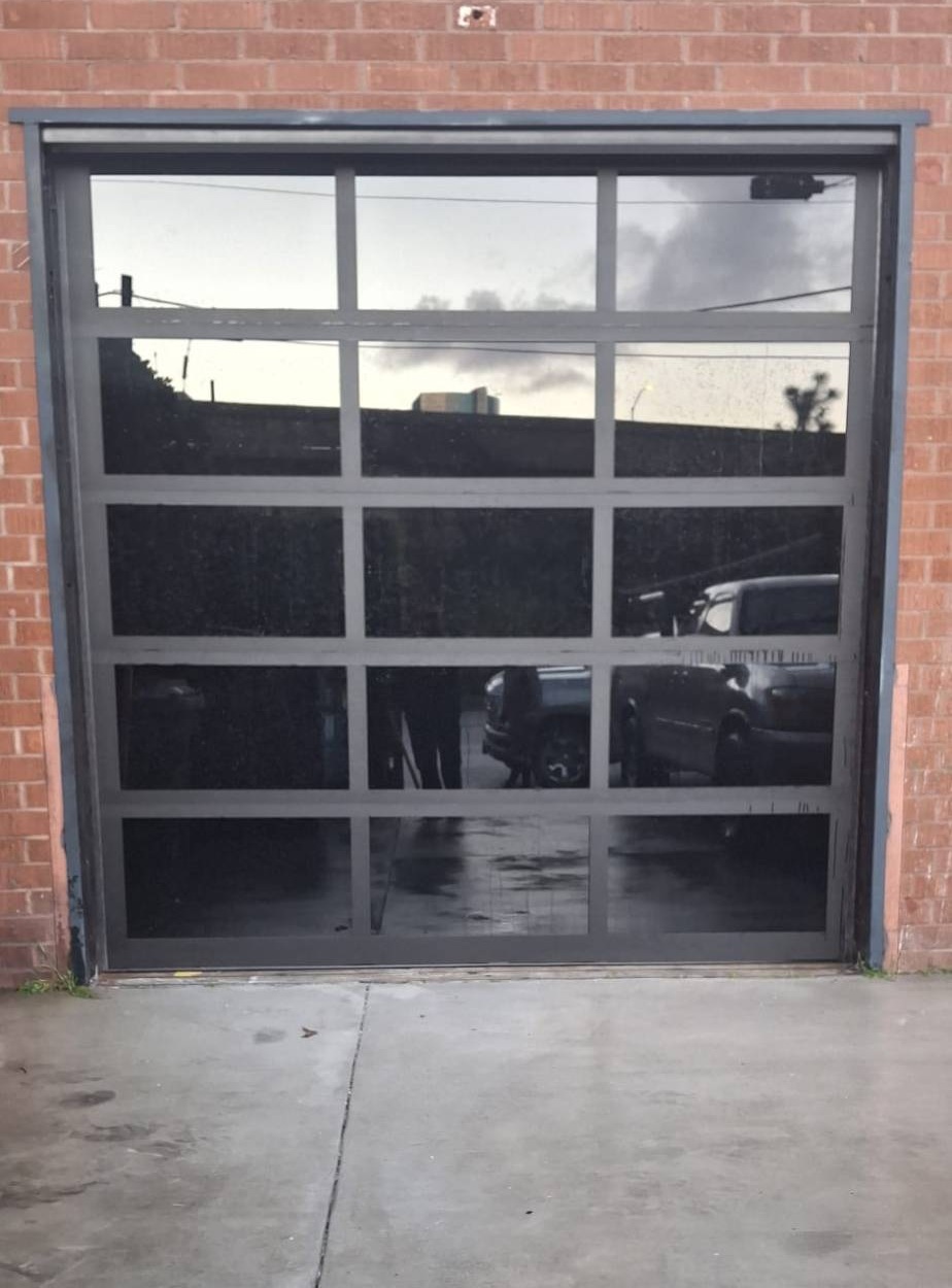 Full-view glass garage door set in a brick commercial building