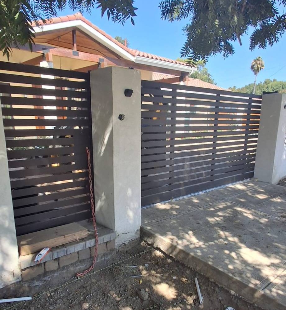 Dark slat pedestrian gate matching a sliding driveway gate, during installation