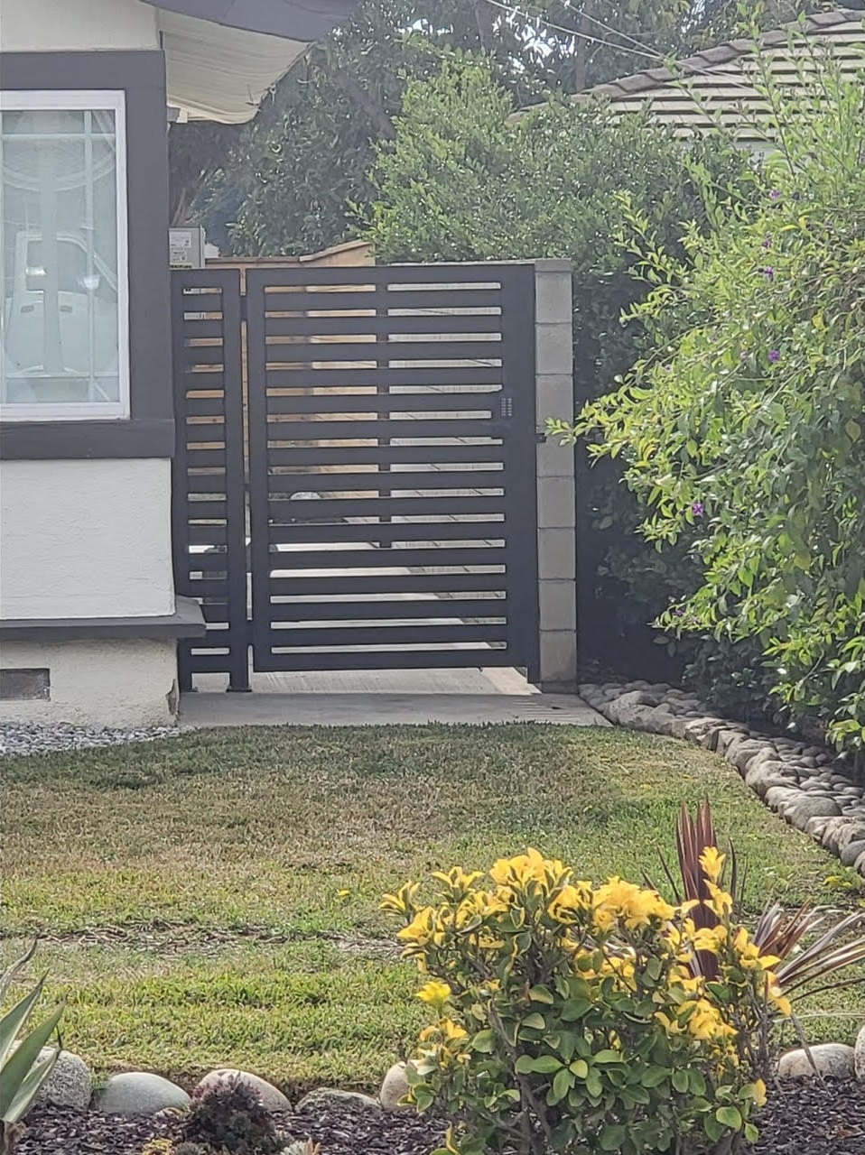 Dark horizontal slat pedestrian gate with matching side panel at a residential side yard entry