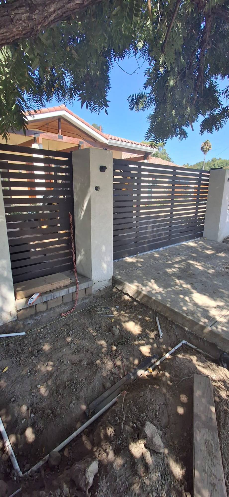 Horizontal slat sliding gate and pedestrian gate between stucco pillars during installation