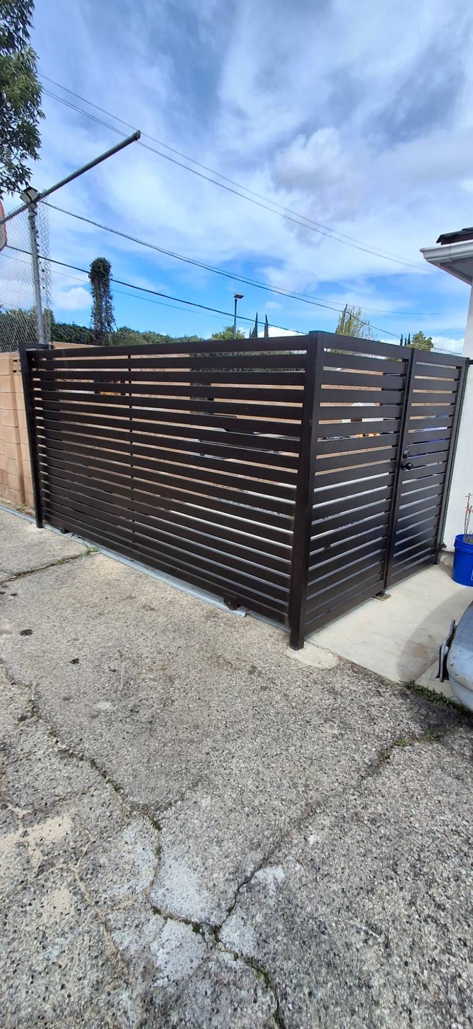 Dark slat wrought iron sliding gate with matching pedestrian gate at a home