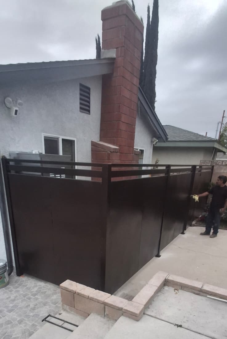 Dark solid-panel privacy fence with horizontal slat band at a residential side yard