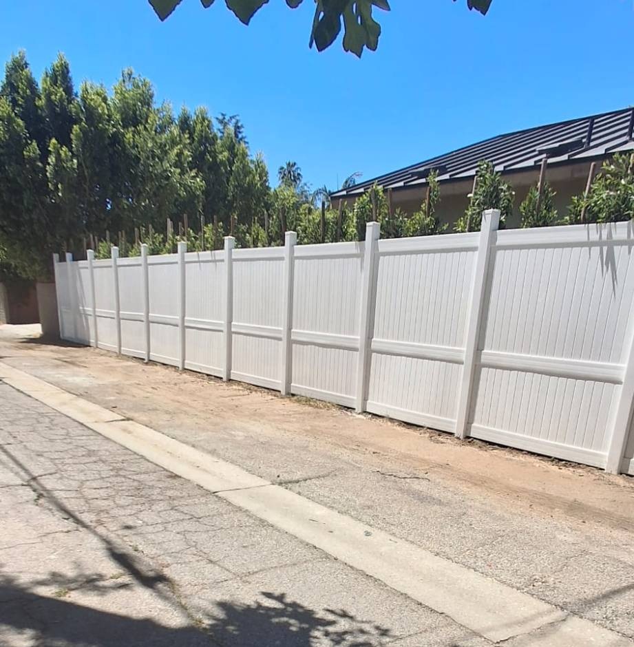 Tall white metal privacy fence installed along a residential alley