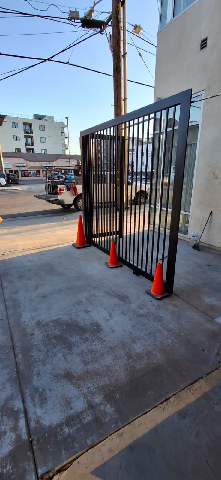 Wrought iron picket swing gate panel set in place at a parking garage